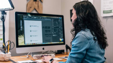 A woman is working on a computer in front of a monitor